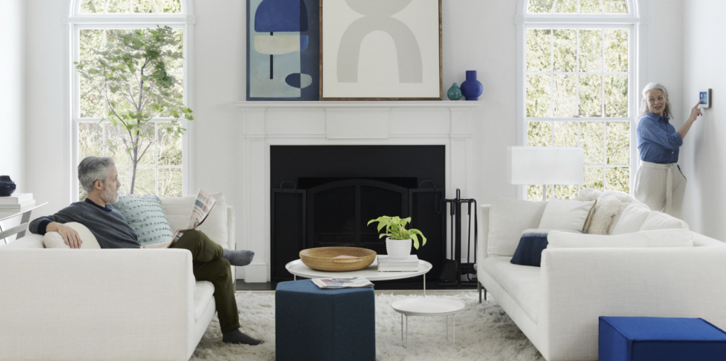 Woman adjusting thermostat while man reads